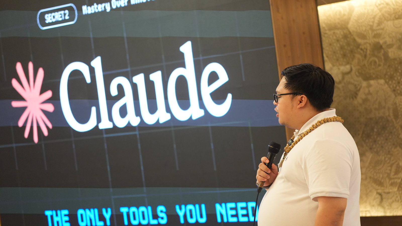 Cris Vinson on stage beside a giant Claude screen reading the only tools you need